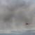 smoke from brush fire passing the American Flag blowing in the wind on rock at Anchor Beach in Milford, CT on 4/9/12