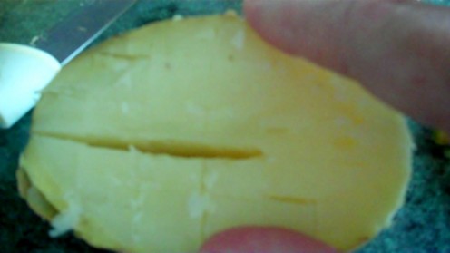 Score the potato with a knife, makes it easier to scoop out of the skin.