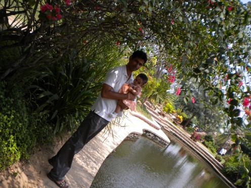 My hubby with our kid by the side of fish pond