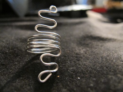 Wrap the wire in four or five coils, then either snip the excess wire or make a design on the lower part of the ring.