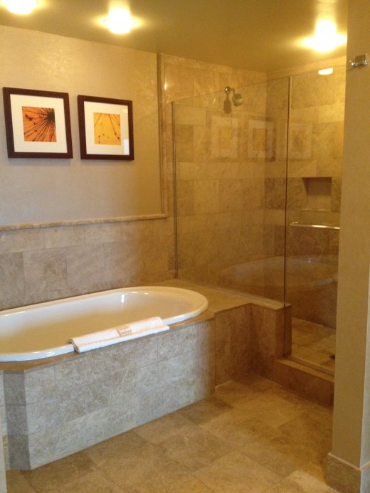 Both the bathtub and shower areas are large and lined in marble and stone tiled. 
