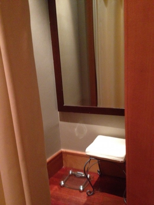 A dressing room is supplied with mirror, bench and weight scale.