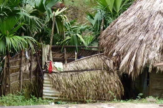 An Embera Indian lady taking a shower in their outdoor shower hut with only cold water coming from the stream up the mountain through a metal pipe.