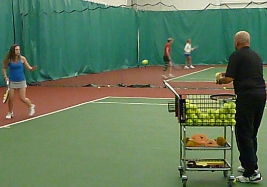 USPTA Teaching Pro Bill Graves feeds balls to young player, Megan, during a lesson.