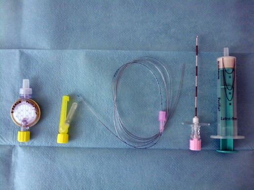 On the left is a filter and connector hub that go on the end of the catheter. The thin tubing in the middle is a typical catheter. The hollow Tuohy needle is next. And on the far right is the syringe that will be used to feel for loss of resistance.
