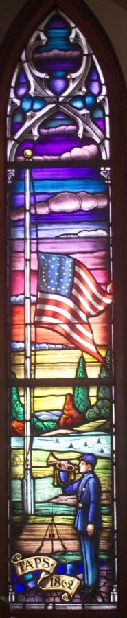 A stained glass window depicting a bugler playing Taps. 
