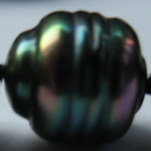 This shows one small, heavily-circled baroque pearl. It is only about 7.5mm big, but shows a real variety of peacock colours, and amazing lustre.  (c) A Jones 2012