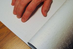 Hand reading a Braille book.