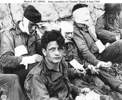 American assault troops of the 16th Infantry Regiment, injured while storming Omaha Beach, wait by the Chalk Cliffs for evacuation to a field hospital for further medical treatment. Colleville-sur-Mer, Normandy, France, 06/06/1944.