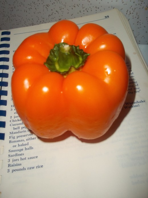 Pretty orange bell pepper sitting on old recipe book.
