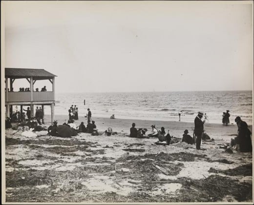 Title: On the Beach in Coney Island Date: 1895 Comments: View of people on the beach at Coney Island.  A pavilion is visible to the left. 
