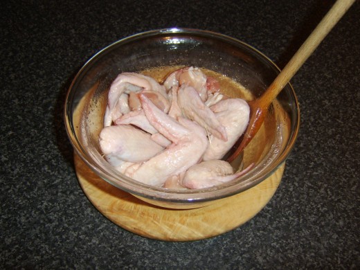 Chicken wings are stirred in oil and salt