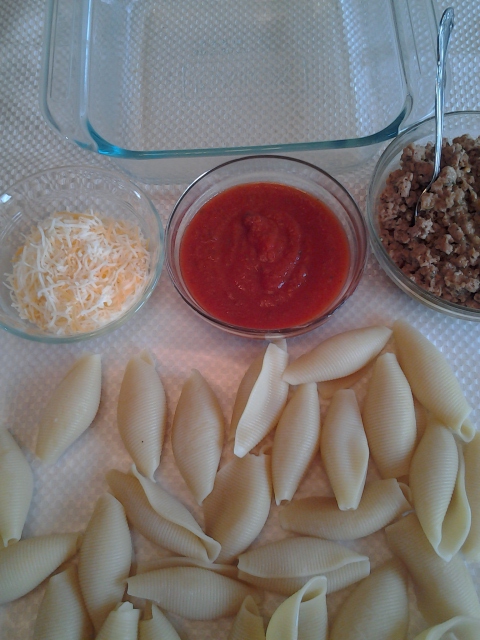 Cooked pasta shells with cheese, sauce and sausage