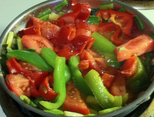 Green & red peppers with tomatoes and scallions, sautéing in extra virgin oil, and Greek seasoning. 