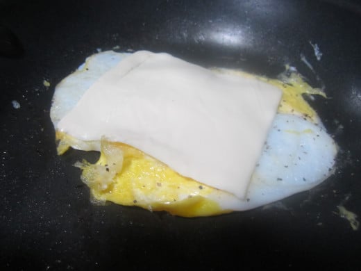 Add cheese to egg in pan to melt slightly.