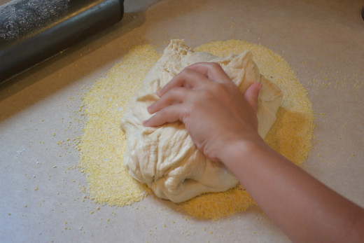 Roll pizza dough in the corn meal and sea salt