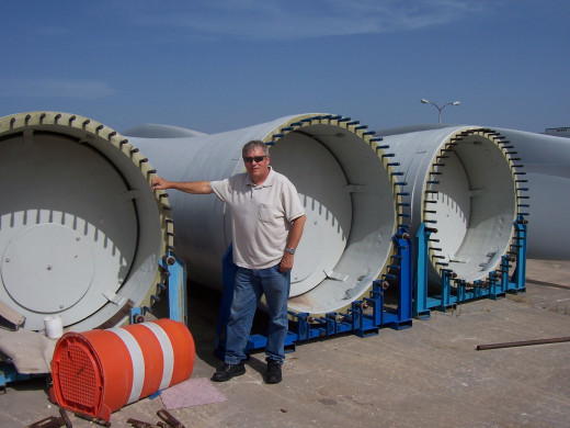 Picture of Kent Britain, the author's father, used with his permission. Kent is standing next to a wind power turbine before the blades have been attached.  Installing renewable energy sources can add back up power sources when the main grid is down.