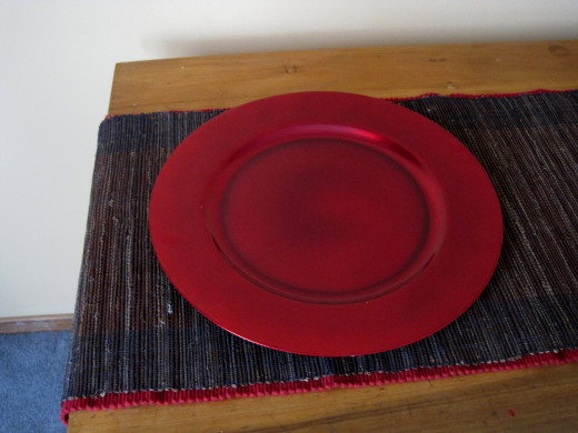 Red charger plate on layered table runners.