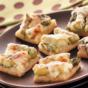 Bit-sized croissant pizza squares with asparagus and cheese on top.