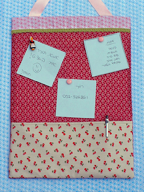 A fabric covered cork board complete with a pocket