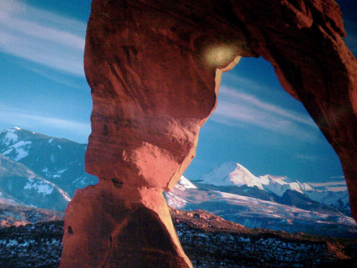 In this image, the rock arch is framing the mountains in the background