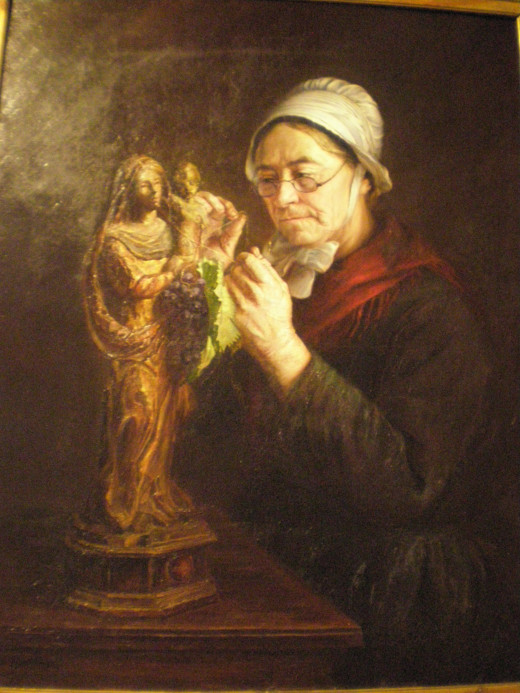 The painting of an old lady tying a bunch of grapes to a Madonna's statue for a holiday. The Madonna with the vine is an image commonly seen in the region.