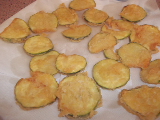 Draining deep fried zucchini on paper napkins. You can use paper towel. This removes a lot of grease. 