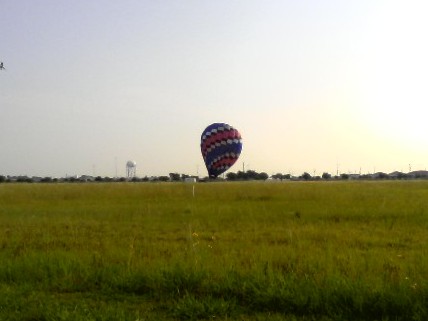 A combination of removing the heat, allowing the air molecules to condense, and allowing some of the air mass to escape out the top, brings the balloon down to earth.