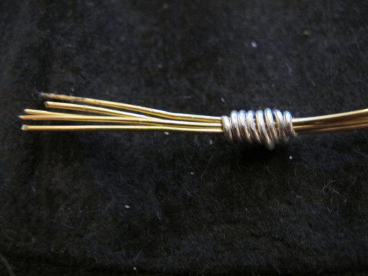 Wrap the first silver wire around the brass pieces, keeping the wrap tight and close.