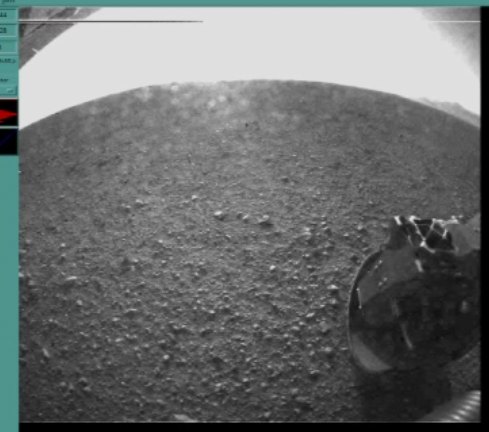 Photo just uploaded from Curiosity getting her bearings. In the distance is rim of Gale Crater under glare of late afternoon sun. (Screencap I grabbed from JPL livestream)