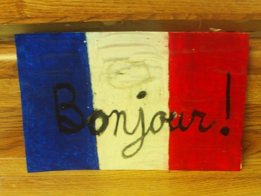 Finish coloring in the red vertical stripe with an oil pastel, and use a black oil pastel to write bonjour on the front of the card.