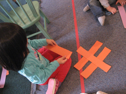 A child uses long and short rectangles to make letters on the floor.