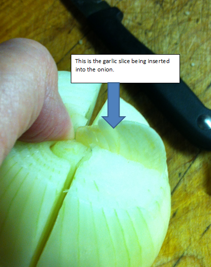 Garlic slice being inserted into onion.