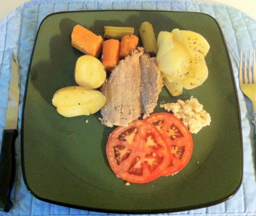 Dinner is served. Baked onions and beef pot roast served with tomato slices and horseradish sauce.
