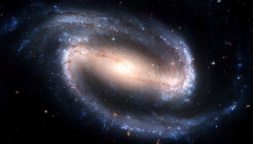A spiral galaxy seen face-on shows a large curved arms of stars.