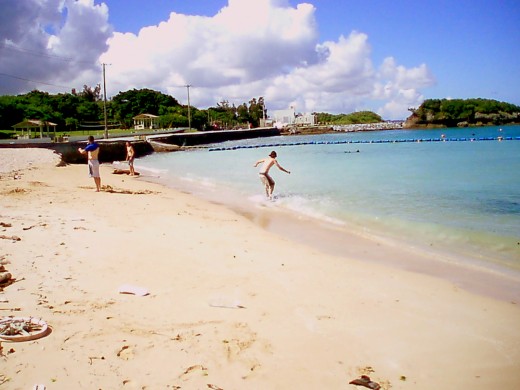 Skimboarding at the Kadena Marina with beach, volleyball net, and pavilions in  background