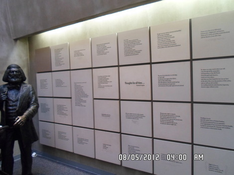 This is a statue of Frederick Douglas standing next to a wall of quotes he made during his lifetime.