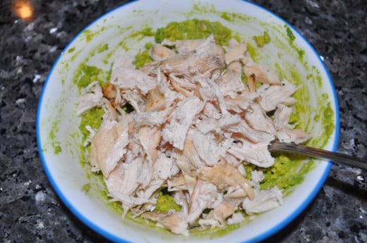 After the avocado has been mashed, shred the chicken into smaller pieces and mix together.