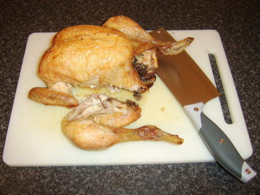 Leg portions are carefully sliced off the chicken