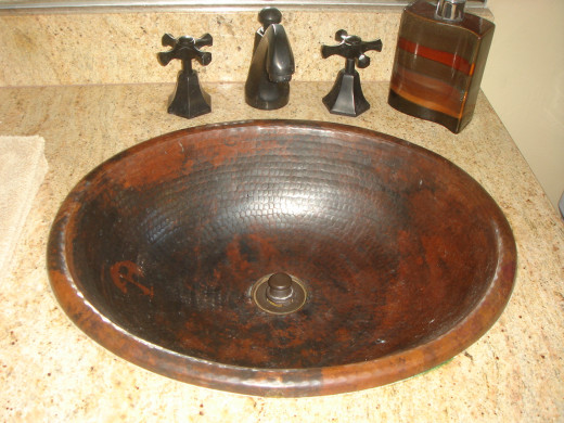 This granite countertop and backsplash form the background for the copper sink.