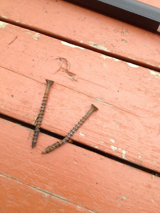 These screws are rusted and mangled.  They'll be replaced with galvanized or coated deck screws to protect the wood from corrosion.