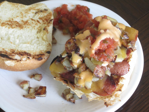 Grilled hot dog sandwich on pan de sal roll with melted cheddar and gouda, salsa and sriracha aioli.