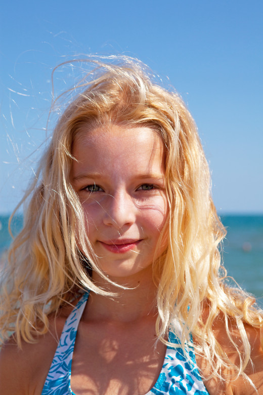 A young blonde in bright sunlight with a shadow cast on her face. Fill-in light techniques could be used to further eliminate the shadows even at the expense of the background. Nonetheless, the shadows are not much of a big deal in this photo.