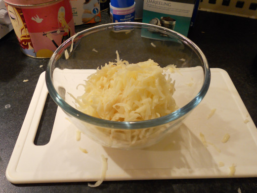 Using a cheese grater, grate both potatoes into a mixing bowl.