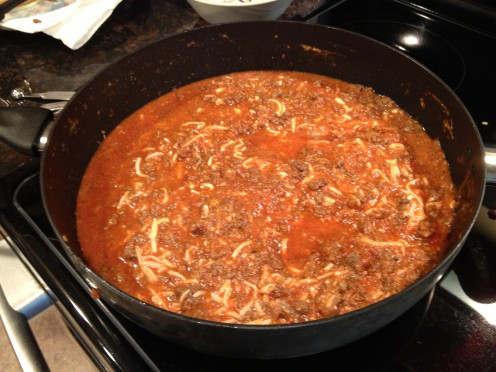 Mix the browned ground beef with spaghetti sauce, mushrooms, water, and the cheeses. 