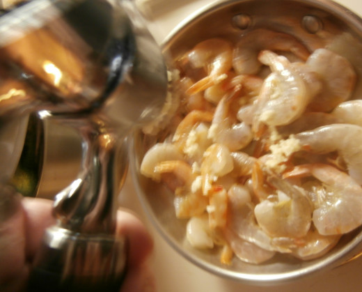 Press garlic onto shrimp in the pan.