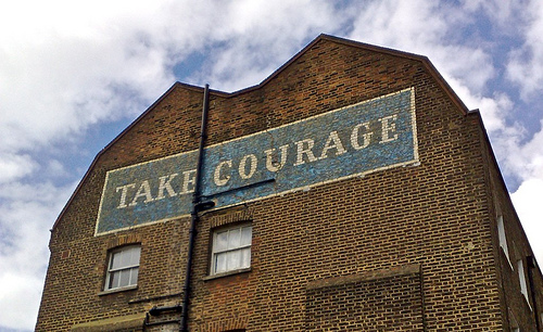 The words "Take courage" on a building.