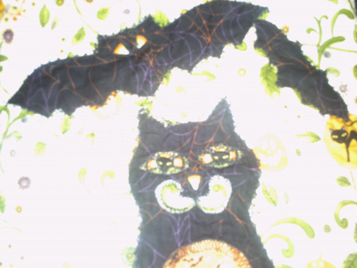 The nose of the cat is just a candy corn cut out, and the cheeks of the cat are the swirls cut around in the light colored cat fabric.  The Bats are cut out of the Black Candy corn fabric freehand and then the Candy Corn is bat eyes and cateye parts.