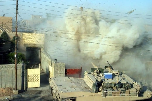 A US Marine Corps (USMC) Marine M1A1 Abrams Main Battle Tank (MBT), 2nd Tank Battalion (BN), fires its main gun into a building to provide suppressive counter fire against insurgents who fired on other USMC Marines during a fire fight in Fallujah, Al