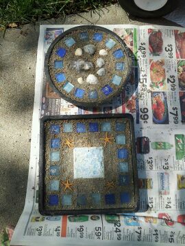 Mosaic cement stepping stones I make for my garden. Using tiles, seashells from beach visits and sea glass from craft stores. Lay the design on the ground or draw it out and then I push them into wet cement.